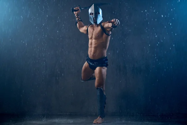 Muscular spartan jumping with sword.