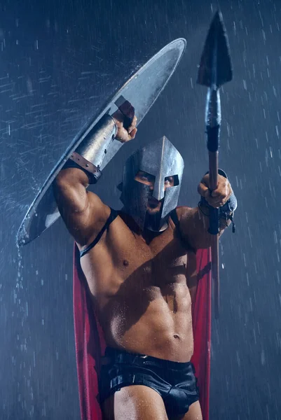 Spartan gömmer sig från regn under sköld. — Stockfoto