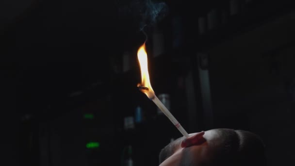 Bearded man sitting in chair with burning paper stick in ear — Stock Video