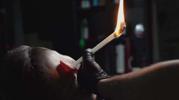 Close up de papel torcido queima varas para fora da orelha homem — Vídeo de Stock