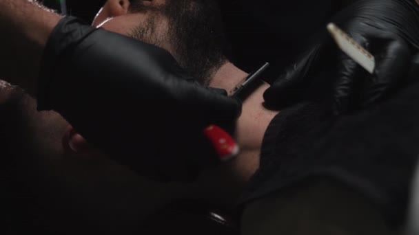 Красавчика с бородой бреют в современном салоне — стоковое видео