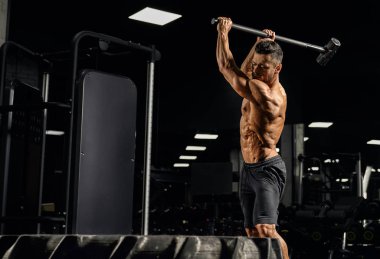 Crossfit sportsman hitting wheel with hammer.