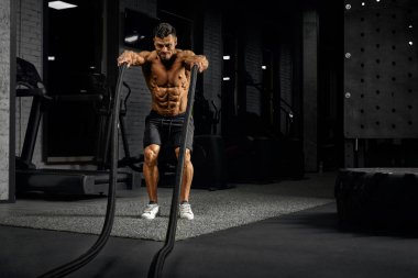 Sportsman doing battle rope training.