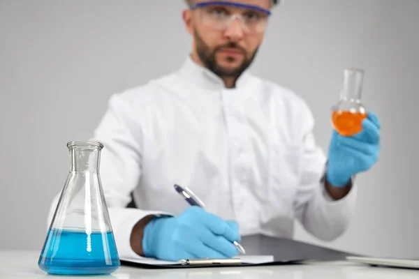 Químico tomar notas enquanto segurando o frasco . — Fotografia de Stock