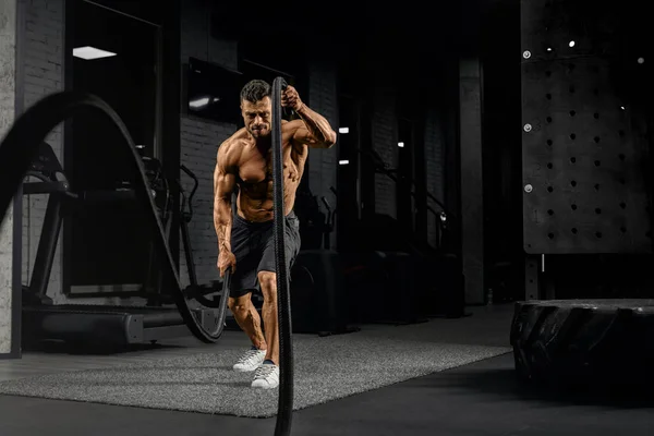 Hombre musculoso haciendo entrenamiento de cuerda de batalla . — Foto de Stock