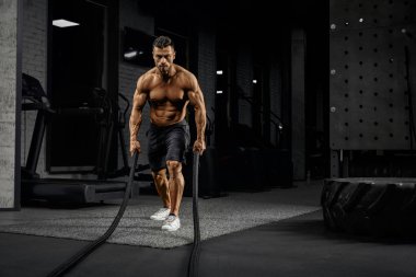 Muscular caucasian man training with ropes.