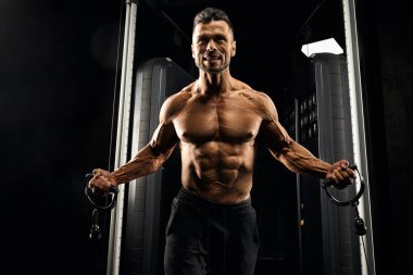 Muscular bodybuilder doing hard crossover exercise.