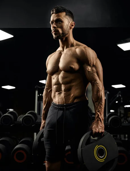 Muscular male bodybuilder holding weights. — Stock Photo, Image