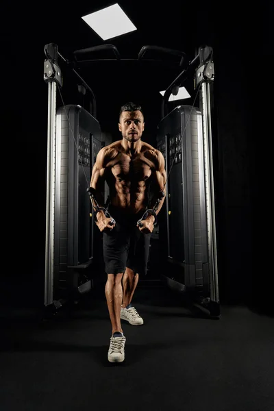 Muscular bodybuilder doing crossover chest exercise. — Stock Photo, Image