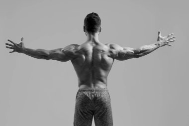 Güçlü genç adam kaslı kollarını açıyor.