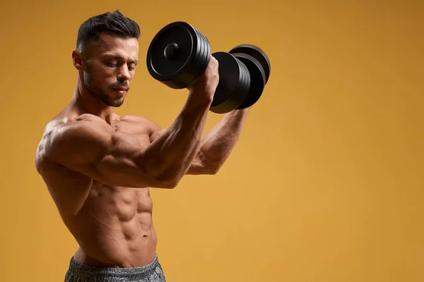 Handsome athletic man pumping up arm muscles — Stock Photo, Image