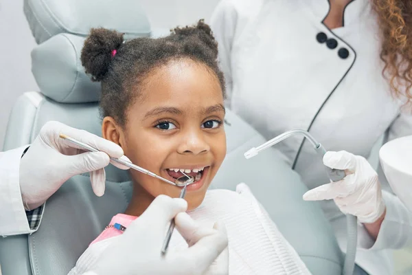 Feliz niño afro en el chequeo regular de los dientes en la clínica dental — Foto de Stock