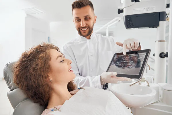 Врач-мужчина показывает рентгеновские снимки зубов на планшете — стоковое фото