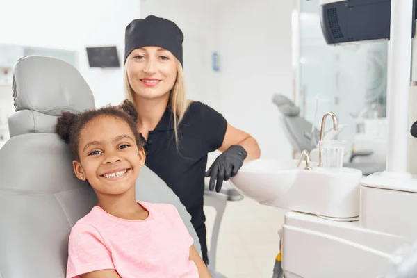 Feliz linda chica africana sonriendo después de la higiene bucal en la clínica —  Fotos de Stock