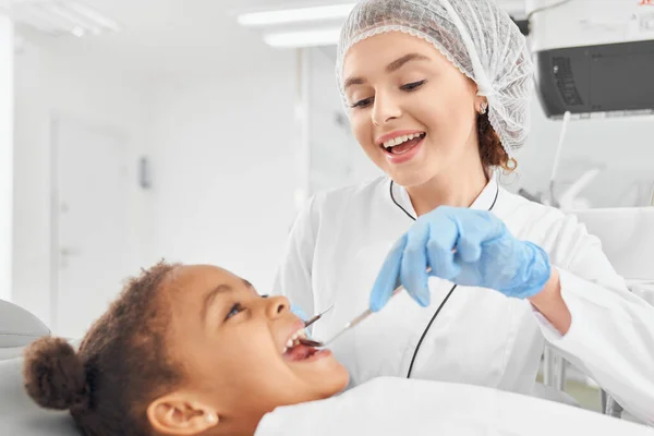 Dentista femenina haciendo chequeo de cavidad oral para chica africana — Foto de Stock