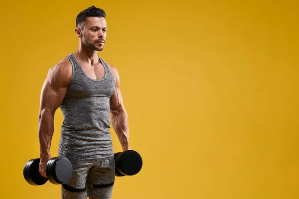 Athletic young man holding dumbbells — Stock Photo, Image