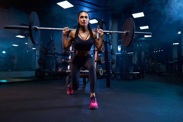 Woman doing squats with barbell.