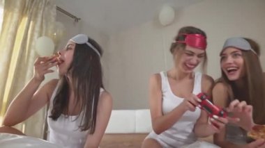 Mutlu kızlar bekarlığa veda partisinde pizza ve video oyunlarıyla rahatlıyor.