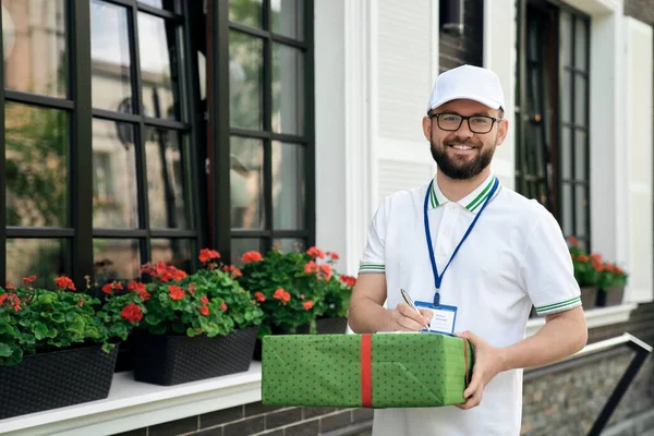 Entregador sosteniendo caja de regalo y carpeta . — Foto de Stock