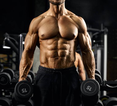 Dambıl taşıyan erkek vücut geliştirici..