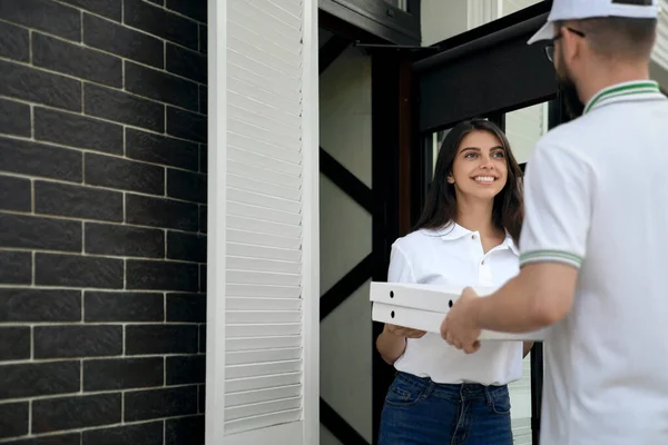 Kvinna som tar emot pizza från kurir. — Stockfoto