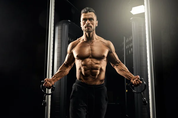 Muscular bodybuilder doing crossover chest exercise. — Stock Photo, Image