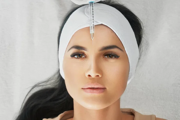 Cosmetologist using syringe to correct female forehead. — Stock Photo, Image