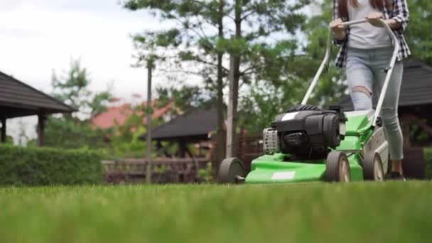 Zblízka zelené sekačky na trávu, která tlačí mladá dáma venku — Stock video