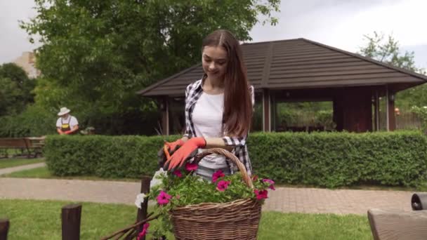 Młoda dziewczyna w gumowych rękawiczkach przycinanie suchych liści z kwiatów — Wideo stockowe