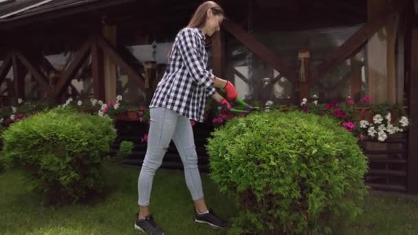 Chica joven trabajando en guantes con tijeras de jardín al aire libre — Vídeo de stock