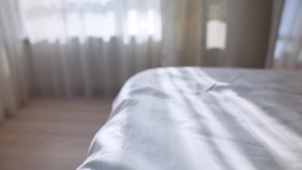 Комфортне біле ліжко з безладною білизною та сонячними ліхтарями — стокове відео