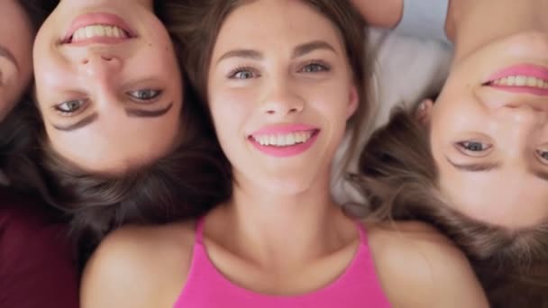Blick von oben auf atemberaubende Frauen, die Kopf an Kopf auf einem großen Bett liegen — Stockvideo