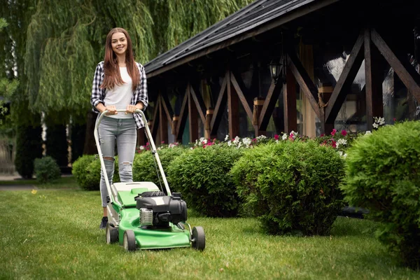 Female gardener using lawn mower.