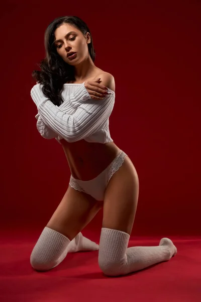 Modelo femenino en suéter posando sobre rodillas . —  Fotos de Stock
