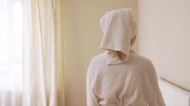 Duştan sonra akıllı telefon kullanan genç kadın..