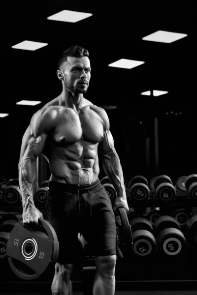 Monochrome portrait of bodybuilder carrying weights. — Stock Photo, Image