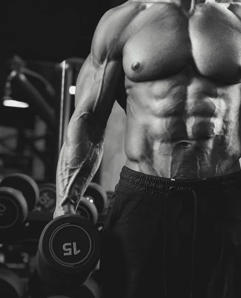 Male bodybuilder holding dumbbell, black and white. — Stock Photo, Image