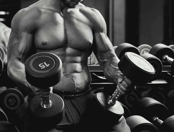 Bodybuilder holding dumbbells on thighs. — Stock Photo, Image