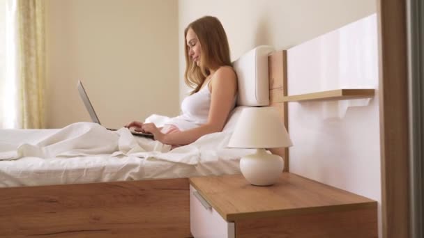 Kvinna skriva på bärbar dator i sängen. — Stockvideo