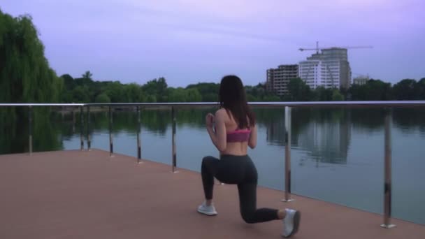 Mujer de fitness haciendo saltos en el muelle del lago . — Vídeos de Stock