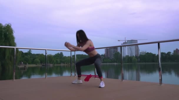 Fitness woman doing squats on lake pier. — Stock Video