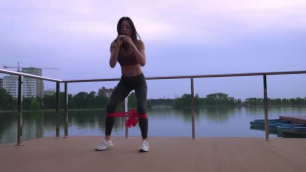 Fitness woman doing squats on lake pier. — Stock Video