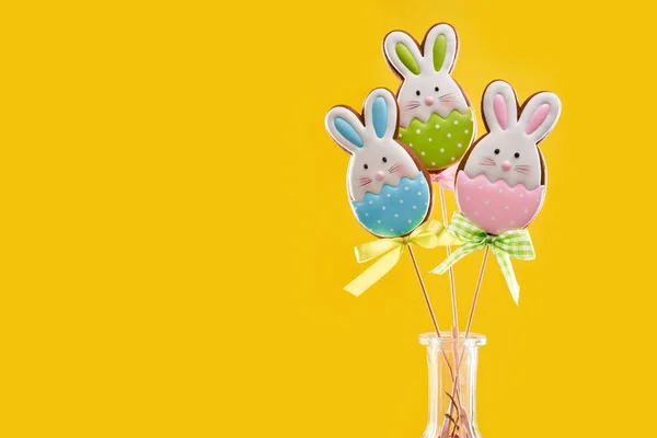 Vivid yellow background with easter gingerbreads on sticks — Stock Photo, Image