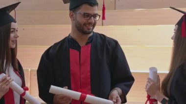 Bornozlu üç mezun ellerinde sertifikalarla konuşuyor..