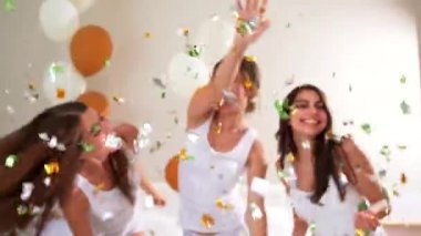 Yatakta konfetiyle dans eden kızlar.