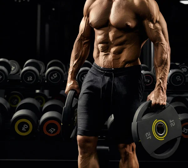 Incognito shirtless male bodybuilder holding weights. — Stock Photo, Image