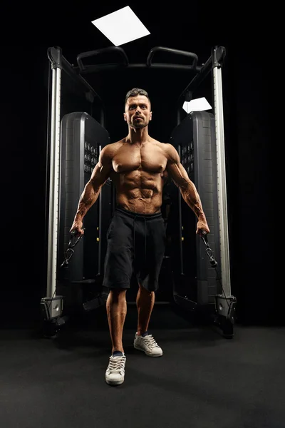 Muscular bodybuilder doing crossover chest exercise. — Stock Photo, Image