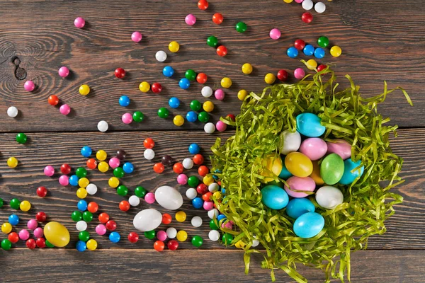 Colorful easter eggs in nest and candies. — Stock Photo, Image