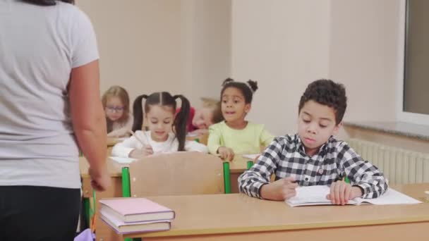 Läraren kollar elevens copybook i klassrummet. — Stockvideo