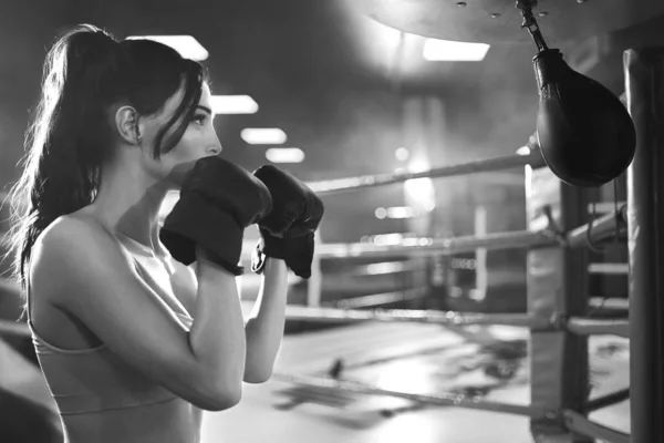 Woman hitting small punching bag, monochrome.